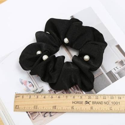 Gir Farmer black mulberry silk scrunchies with pearl accents placed next to a ruler on a magazine page