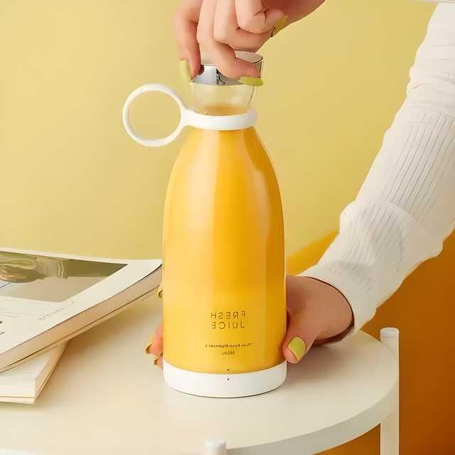 Yellow compact blender for travel with a white handle and lid held by person with yellow nails