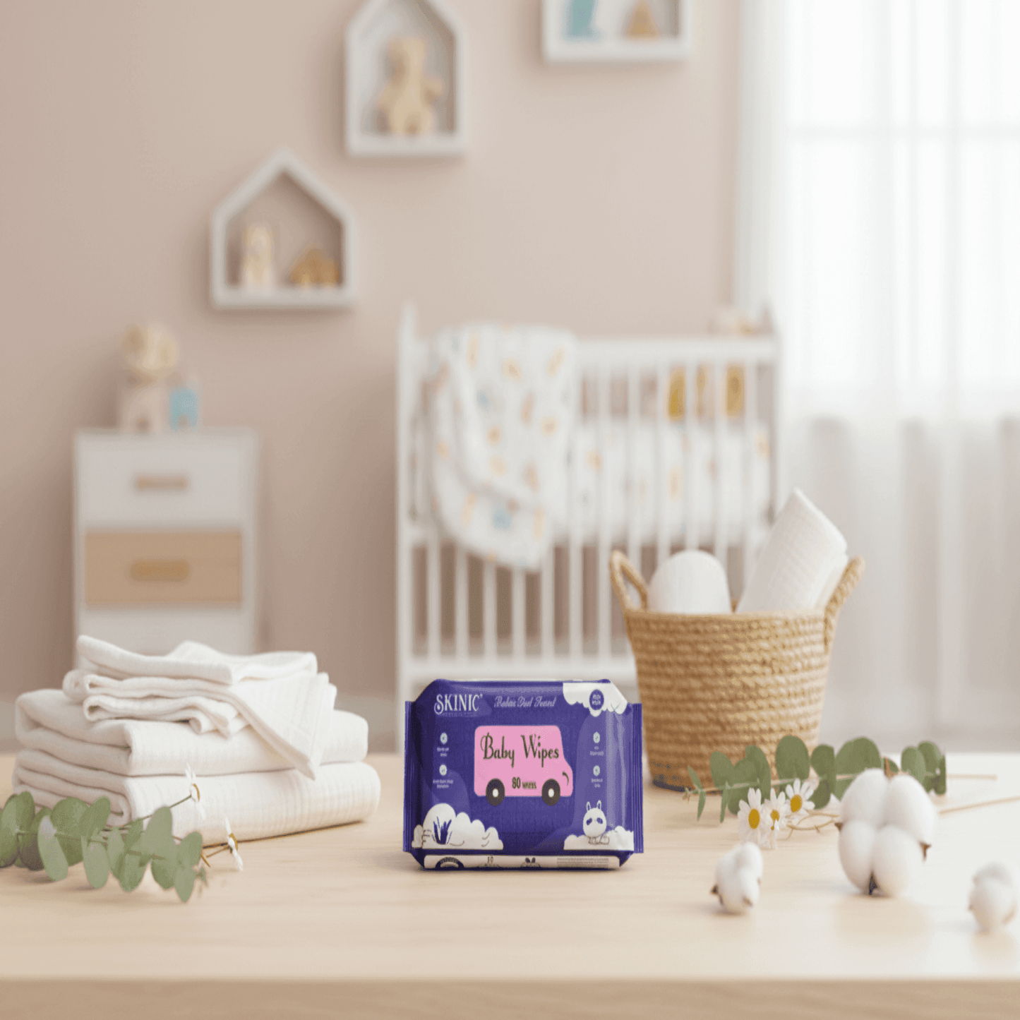Box of baby wipes on a table in a nursery setting with crib and decor.