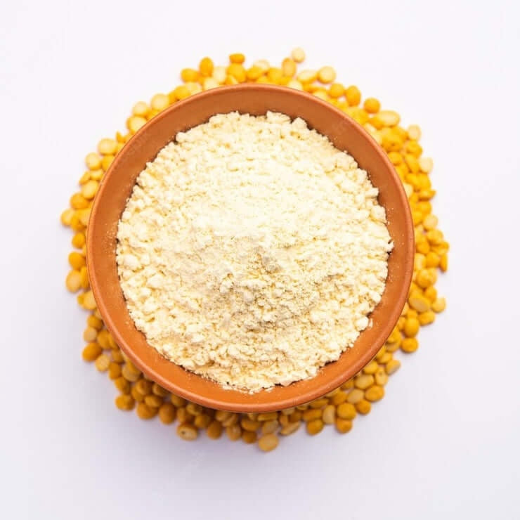 Bowl of organic besan flour surrounded by raw chickpeas for healthy cooking
