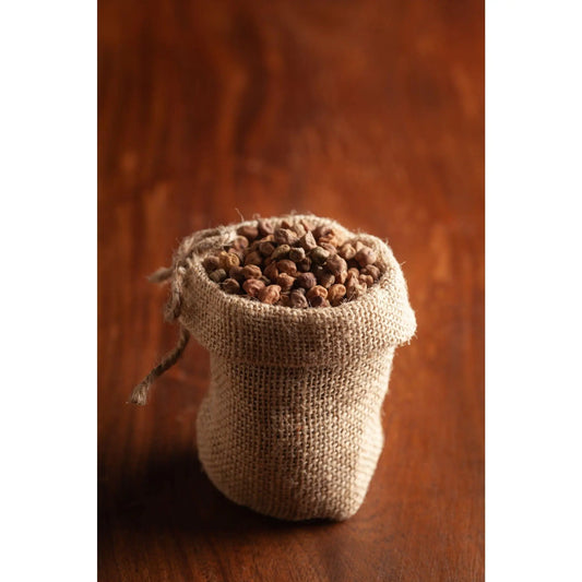 Small burlap sack filled with organic black desi channa on wooden surface by THE GIR FARMER
