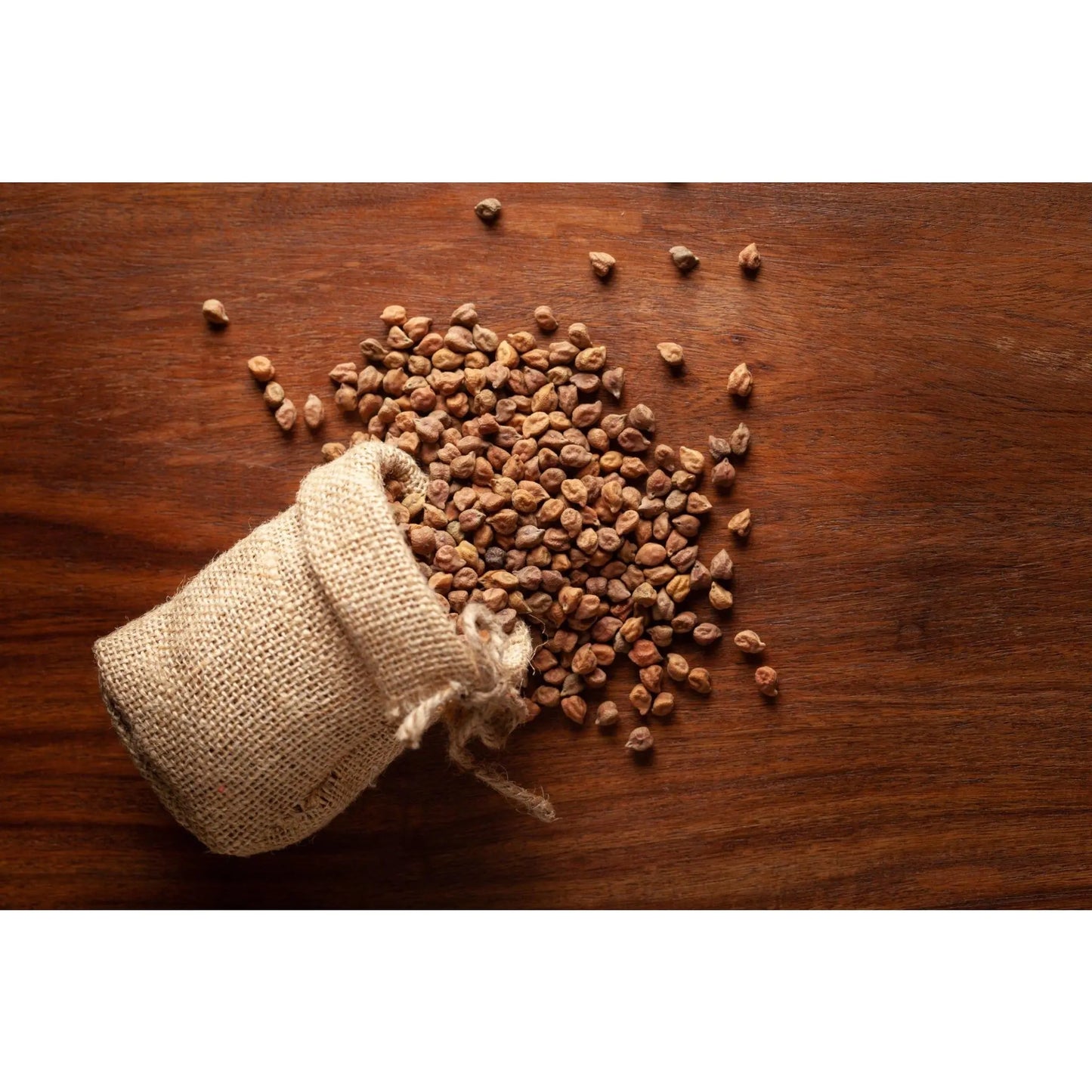 THE GIR FARMER organic black desi channa spilled from a burlap sack on wooden surface