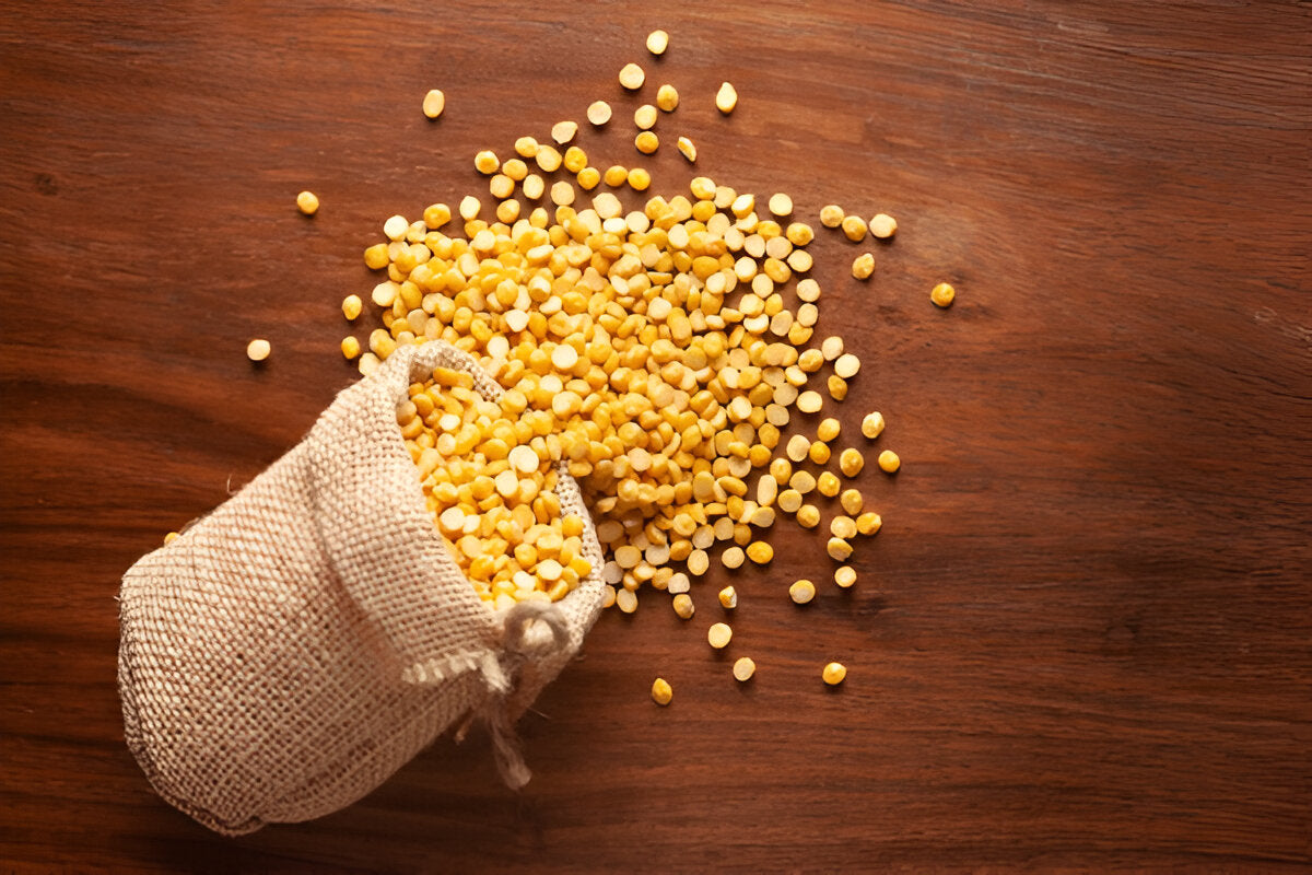 Organic chana dal spilling out of a burlap sack on a wooden surface from THE GIR FARMER