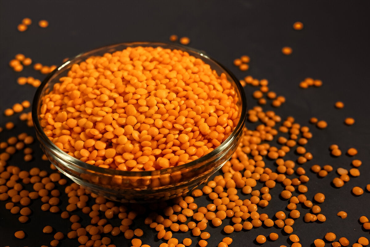 Bowl of orange organic masoor dal lentils by THE GIR FARMER on black background