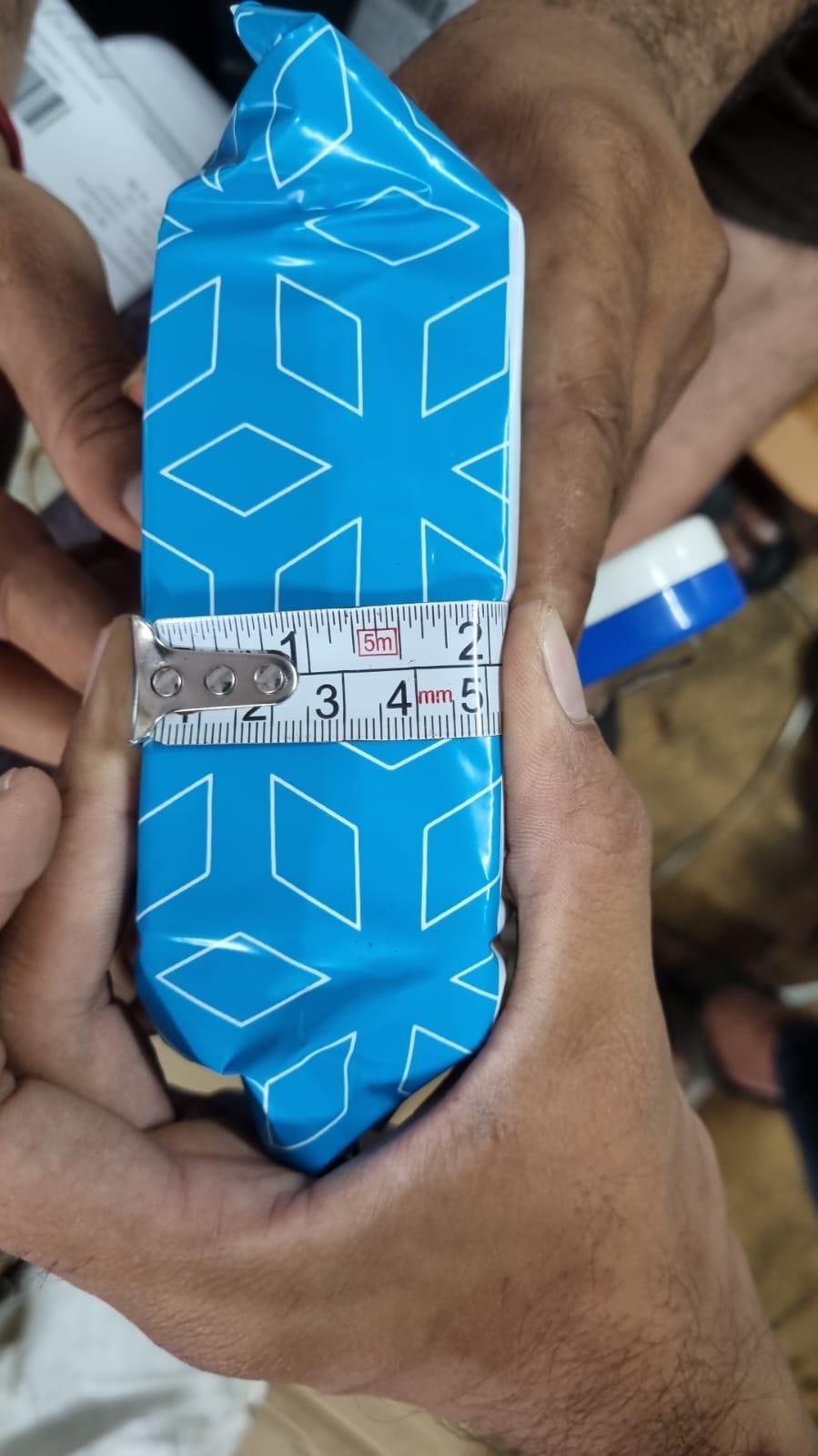 Blue packaging of organic potting mix held with a measuring tape for size reference
