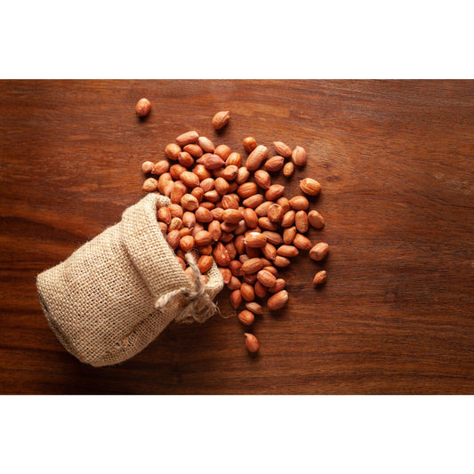 Organic raw peanuts spilling out of a burlap sack on a wooden surface from THE GIR FARMER