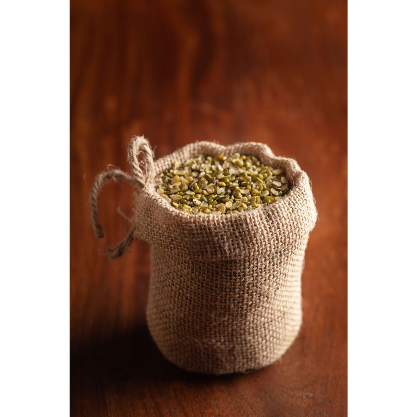 Jute sack filled with organic split moong dal showcasing its green split lentils