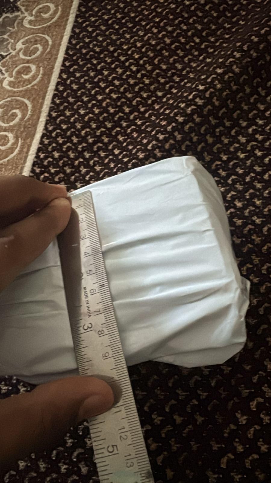 Unboxed bee venom skin cream package being measured with a ruler for size reference