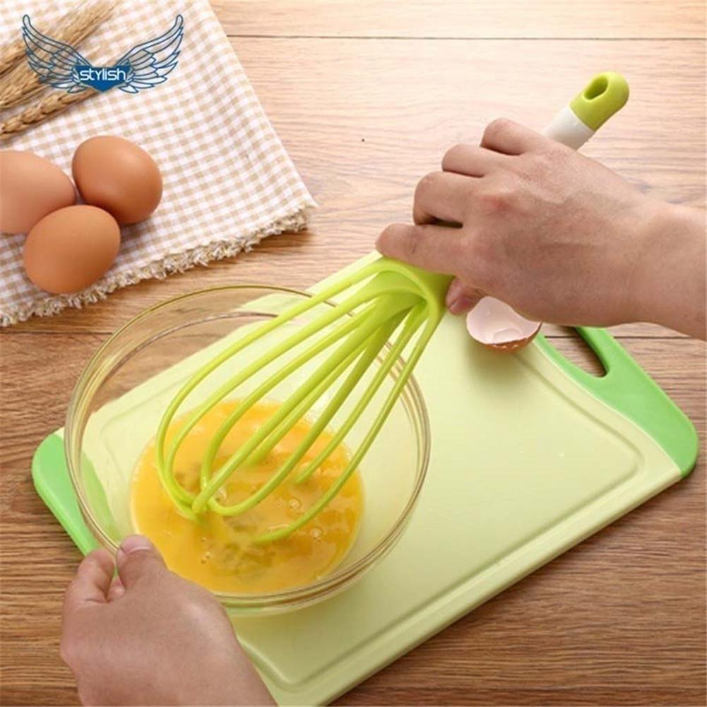 Your Brand plastic balloon whisk mixer in use, mixing eggs in a glass bowl on a cutting board