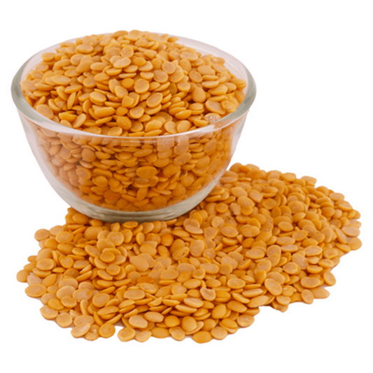 Glass bowl filled with pure natural tur dal lentils spilling onto white surface