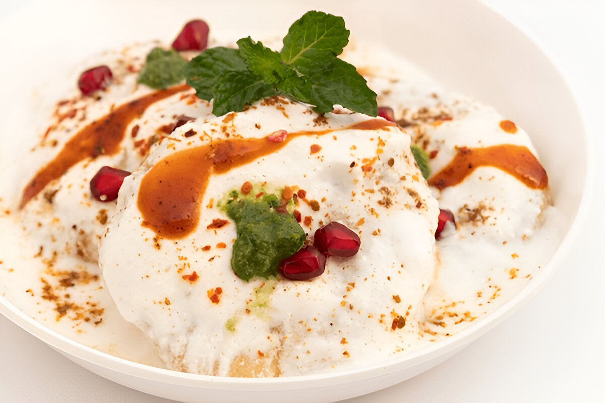 Delicious Indian dish made with pure urad dal for sale topped with yogurt, chutney, and pomegranate seeds