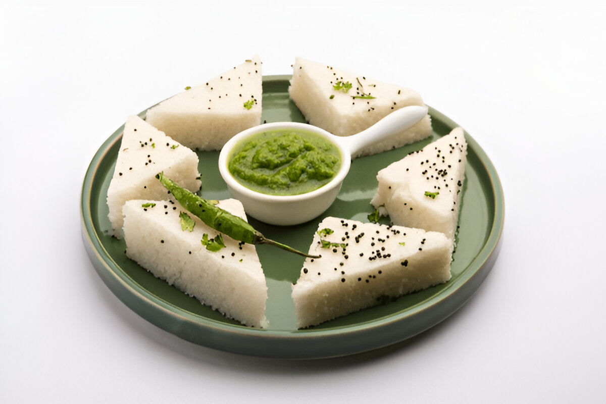 Plate of white triangular idli pieces served with green chutney and green chili showcasing pure urad dal for sale