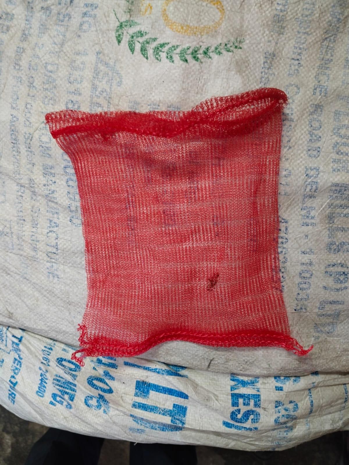 Red mesh produce bags for groceries made by THE GIR FARMER displayed on a textured background