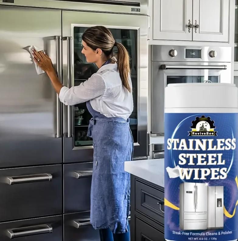 Woman using stainless steel wipes for fridge and appliances to clean a stainless steel refrigerator in a modern kitchen