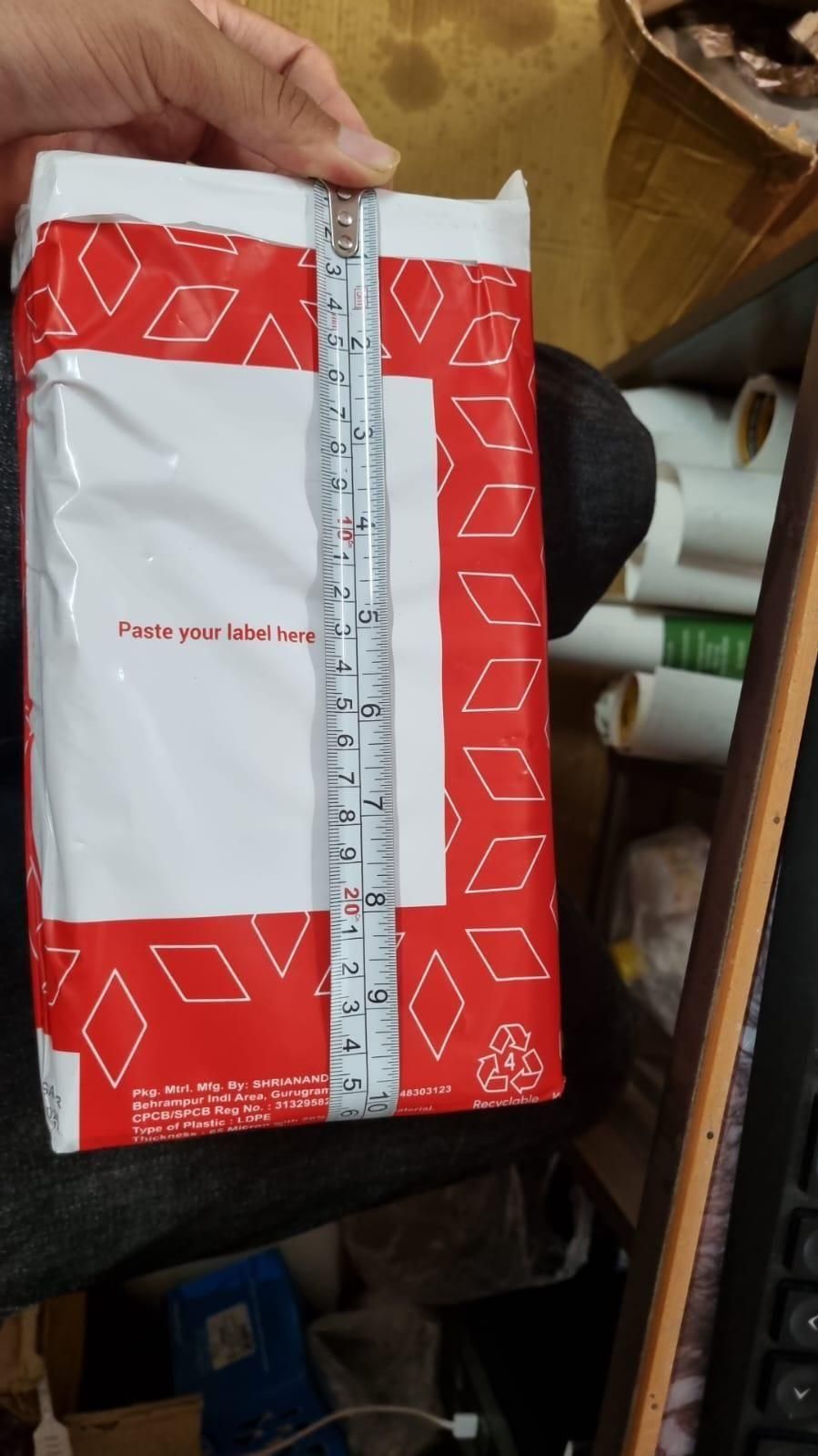 Hand holding red white shipping pouch measured with tape showing packaging for pet hair removal gloves