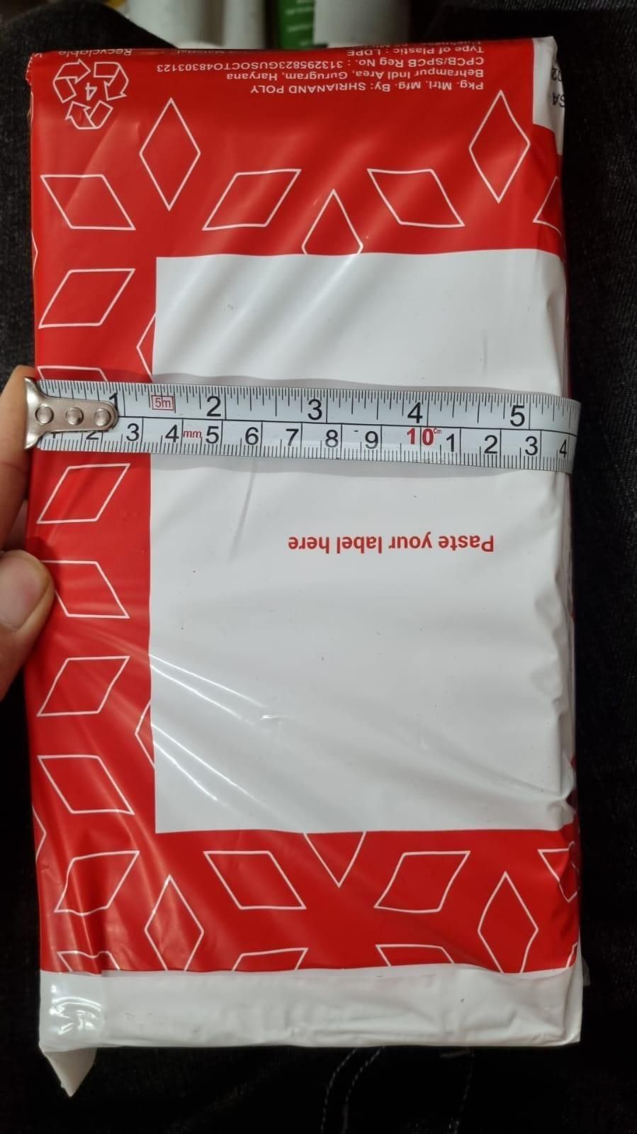 Red and white poly mailer holding pet hair removal gloves with blank address label and tape measure across