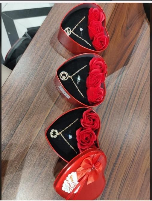 Romantic jewelry and flower combo featuring gold necklaces and red roses in heart-shaped red boxes