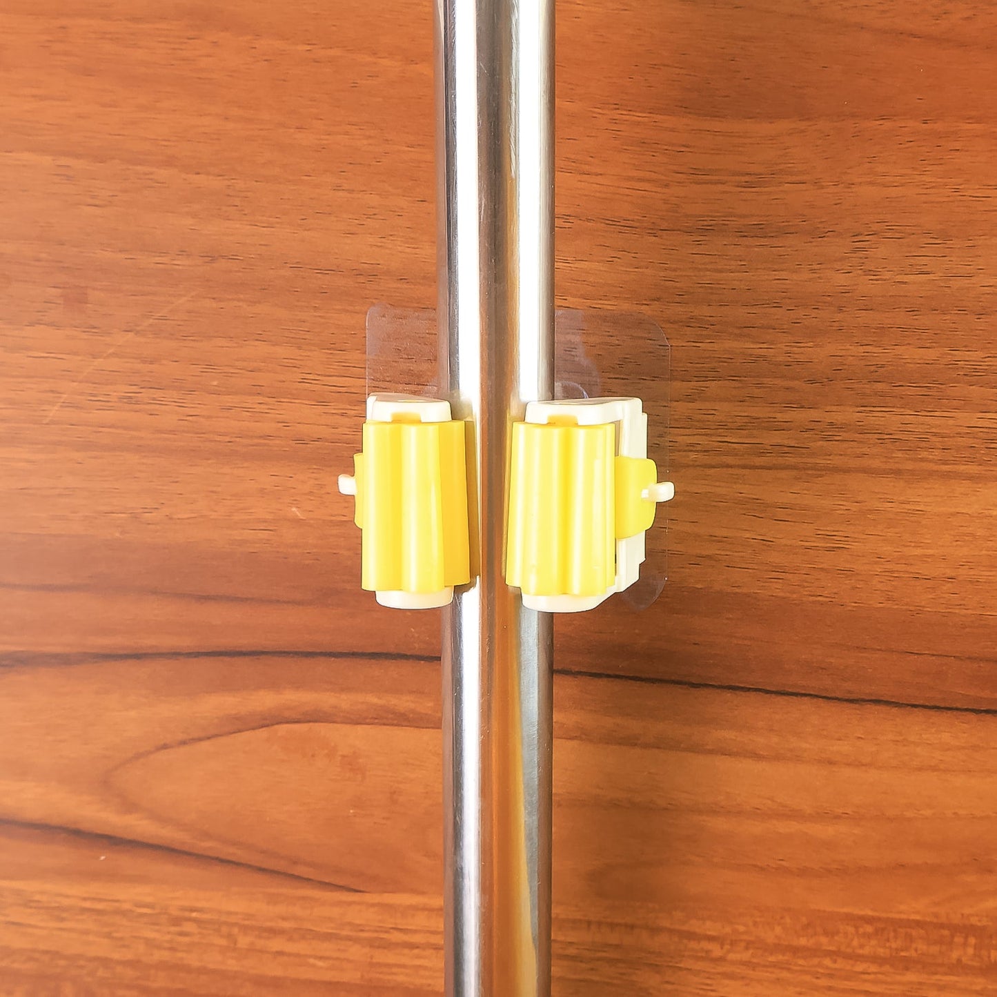 Self adhesive mop holder in yellow, designed for easy mounting on various surfaces and storing mops securely