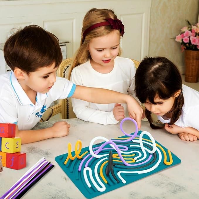 Three kids playing with a colorful sensory development board for kids on a table indoors