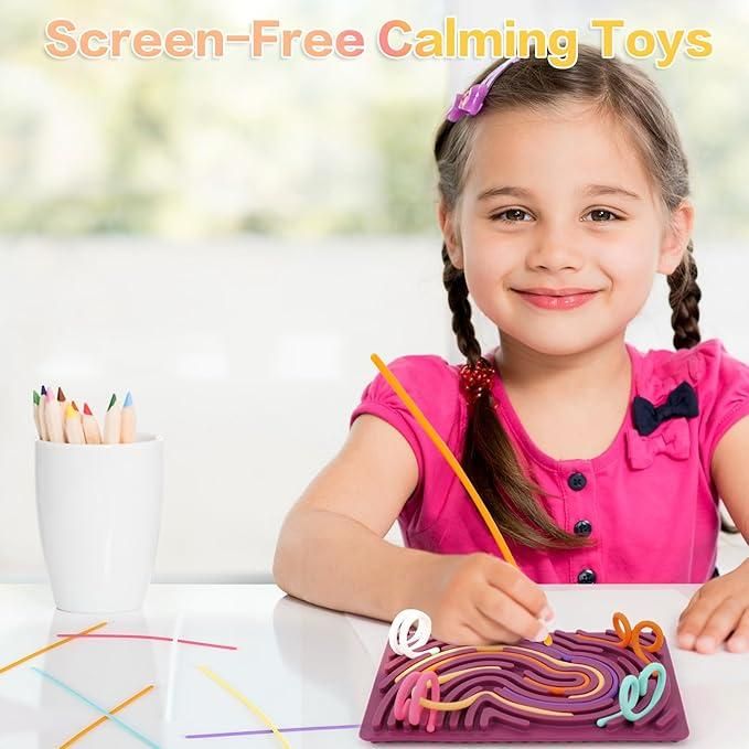 Young girl playing with a sensory development board for kids at a white table with colored sticks