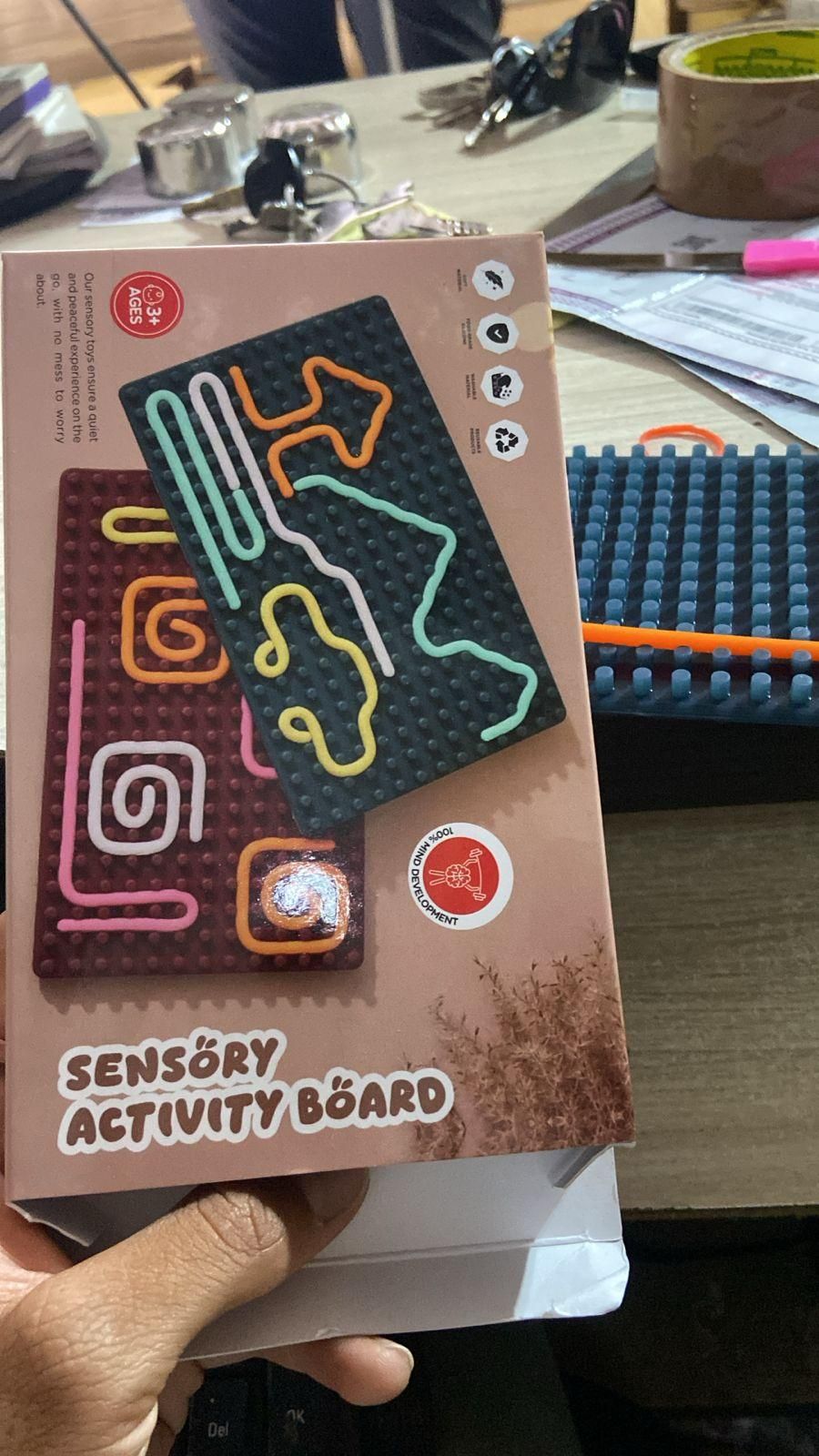 Sensory development board for kids with colorful tracks and shapes on a textured activity board