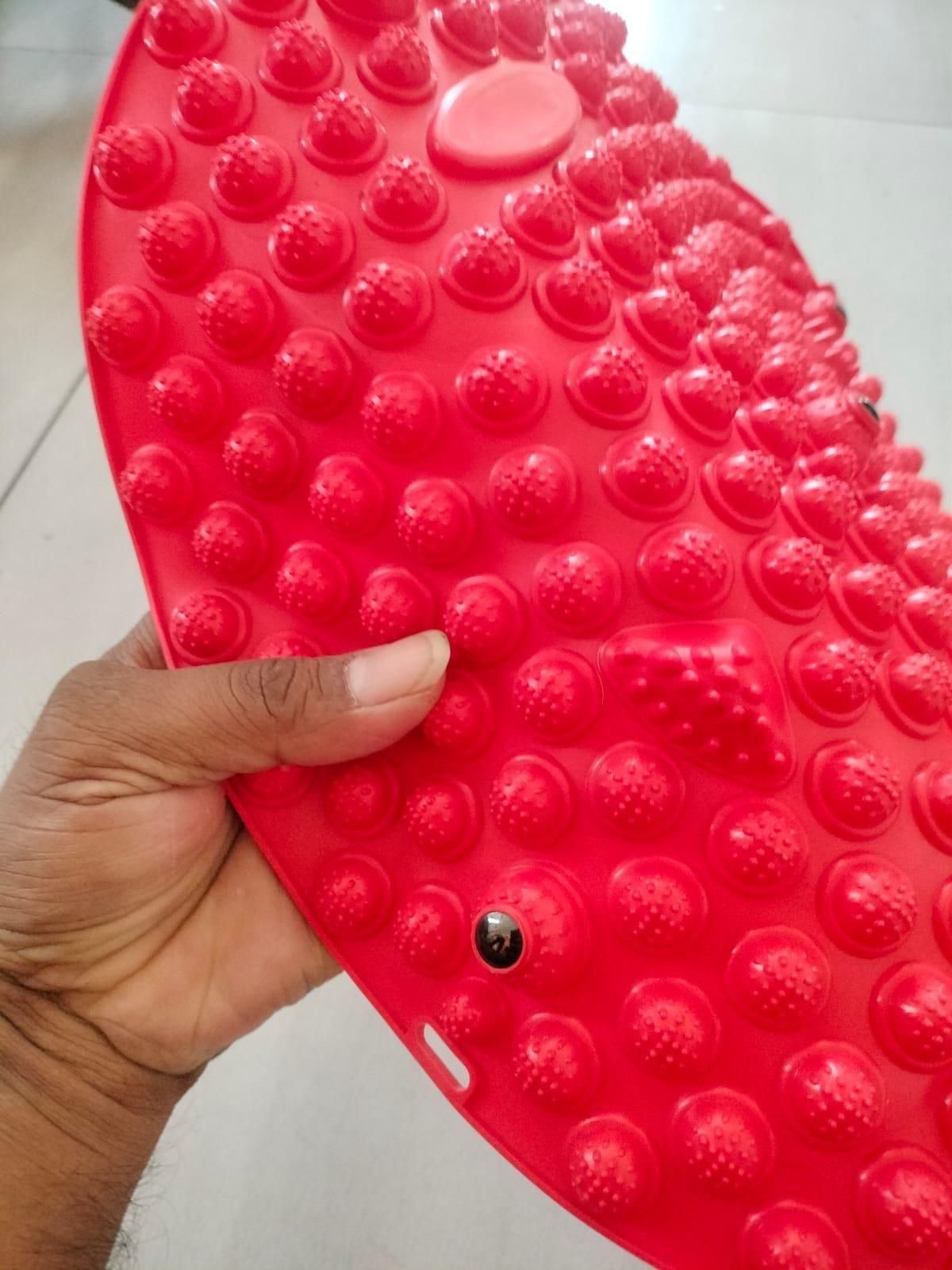 Hand holding red silicone foot massage pad with textured nodules for improved foot comfort