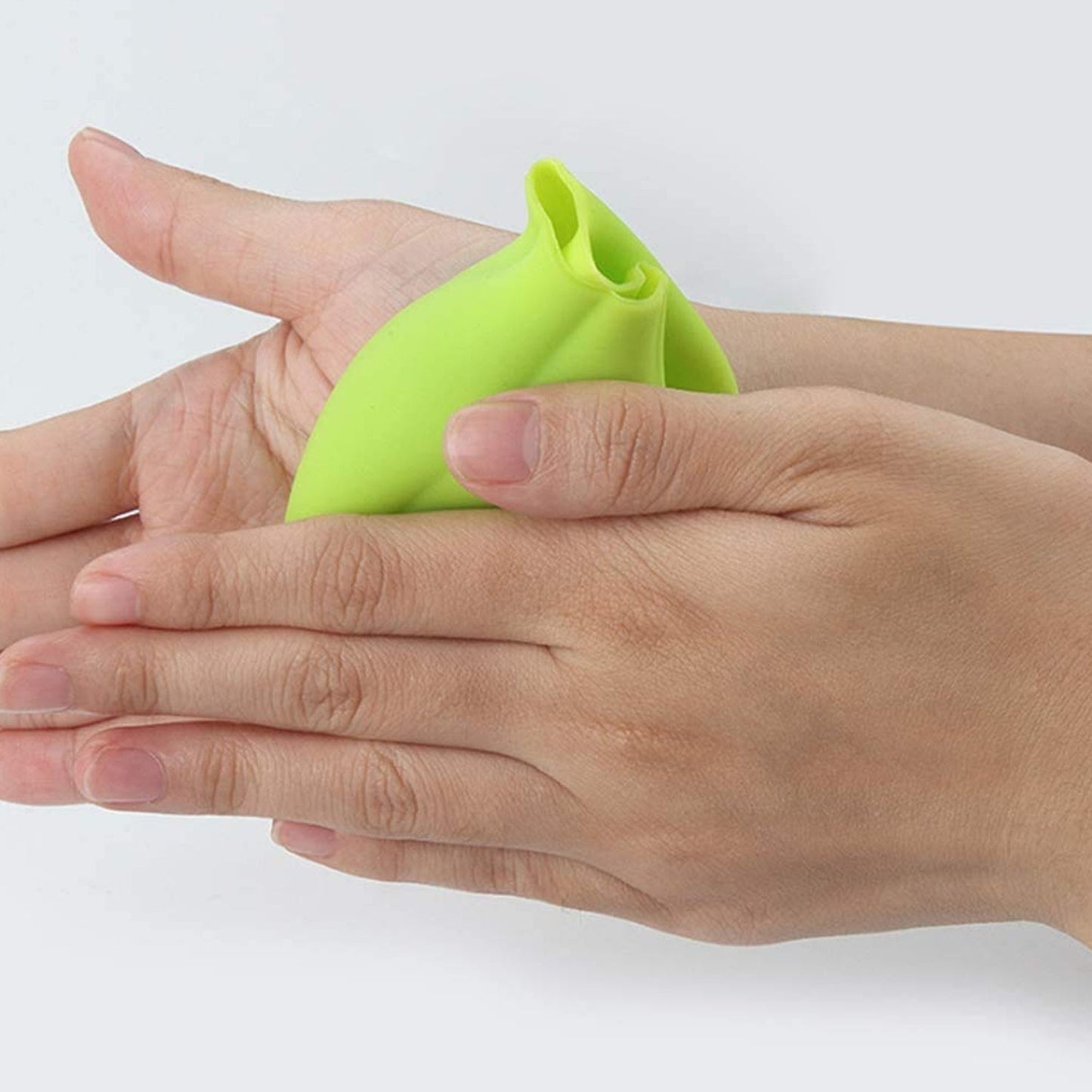 Green silicone garlic peeler being used to easily remove garlic skins at home