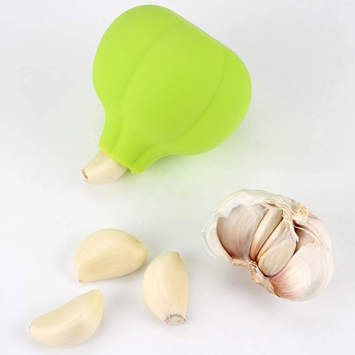 Green silicone garlic peeler with garlic cloves on a white surface for easy garlic preparation