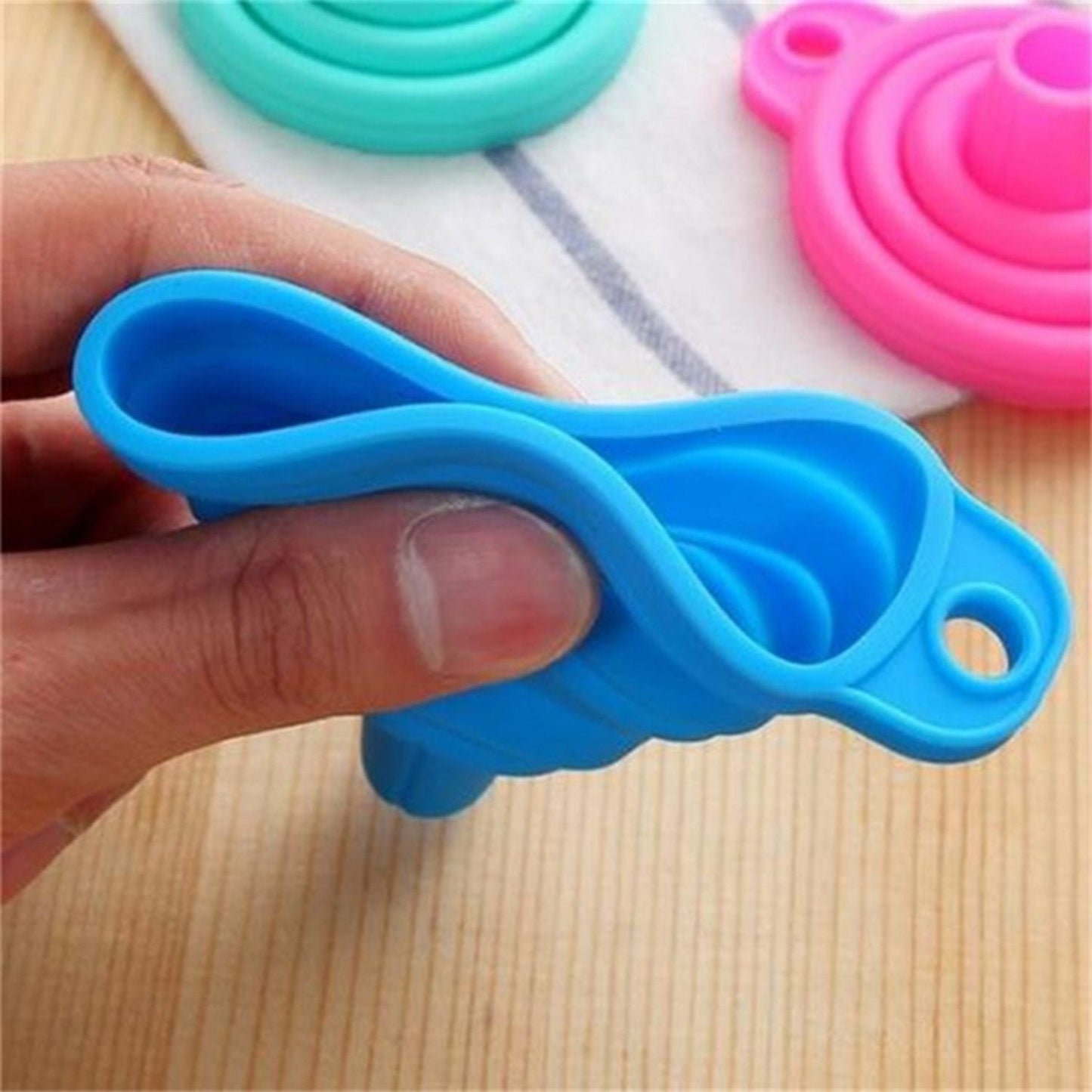 Blue silicone kitchen funnel designed for easy pouring and storage, with a hand grip for convenience