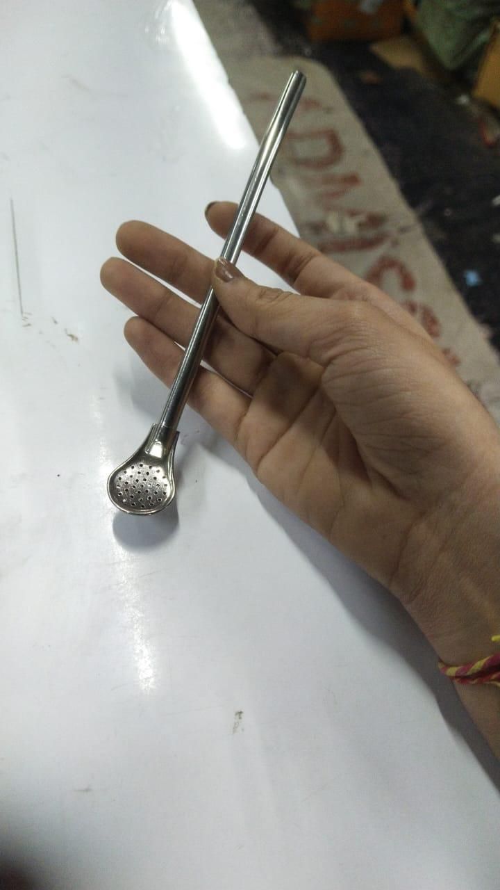 Hand holding stainless steel drinking straws with a unique flat spoon-like end for easy cleaning