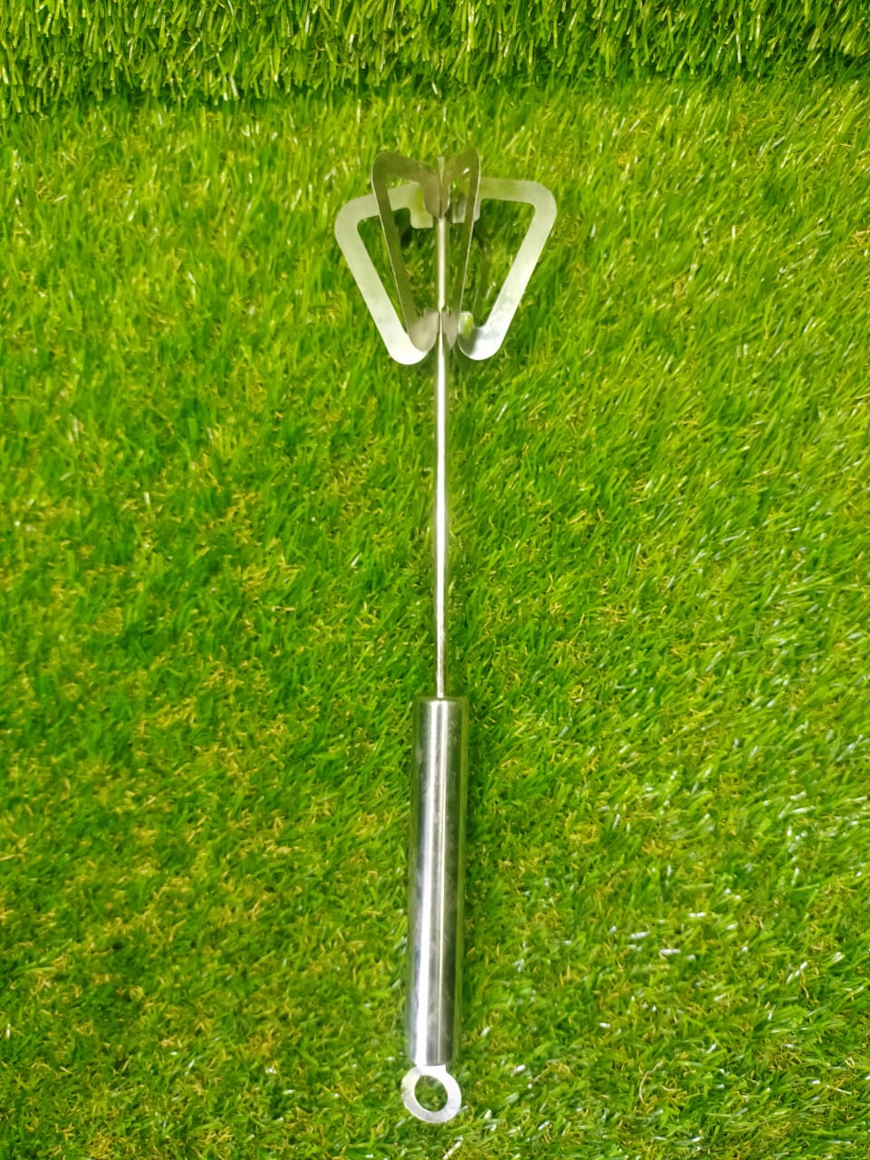 Stainless steel hand blender with ergonomic handle and dual blade design on green background