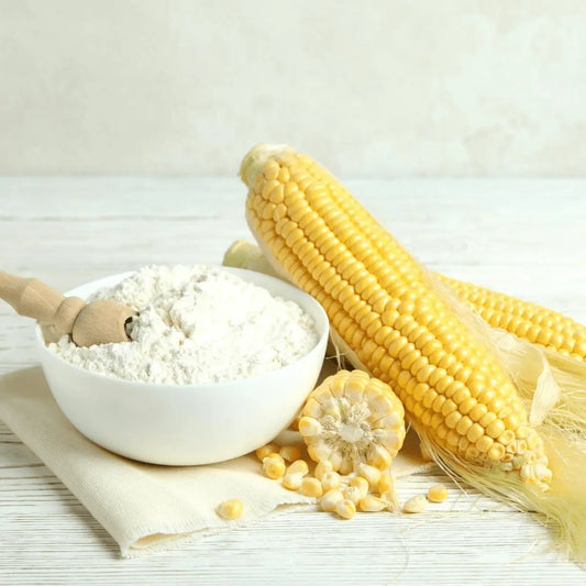 THE GIR FARMER naturally processed corn flour in a bowl with fresh corn cobs beside it