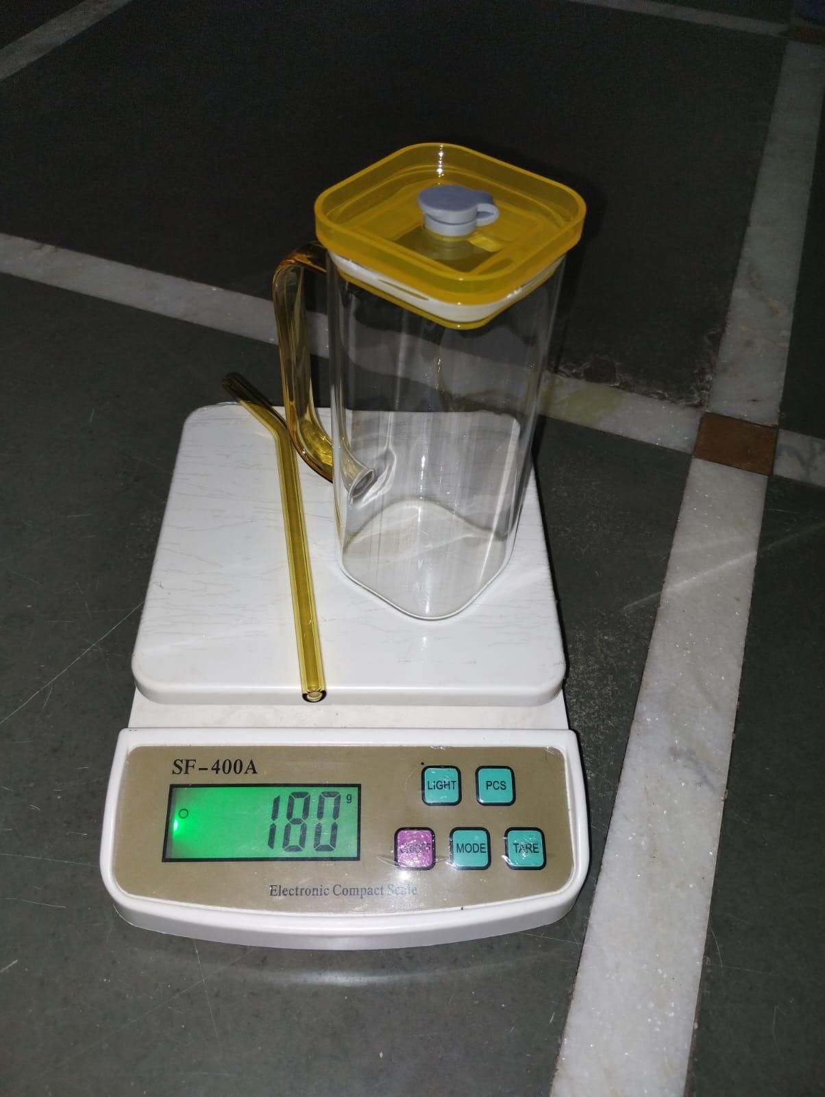 Clear glass tumbler for boba tea with yellow square lid and straw on digital scale showing 180 g