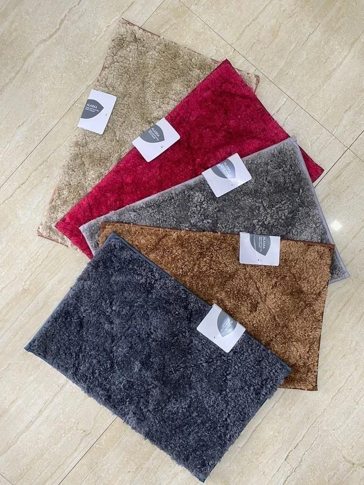 Set of soft fluffy anti slip door mats in beige red gray brown and black colors on tiled floor