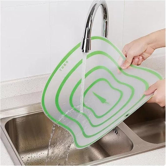 Flexible food prep board for vegetables being rinsed under a sink faucet with water flowing