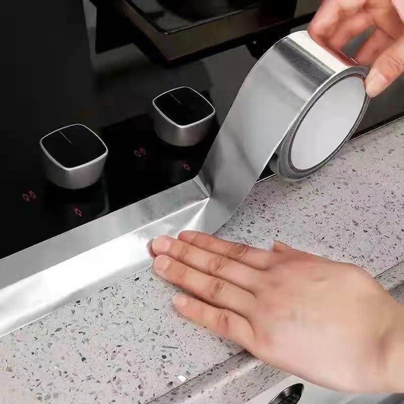High temperature resistant aluminum tape being applied around a stove edge for heat protection