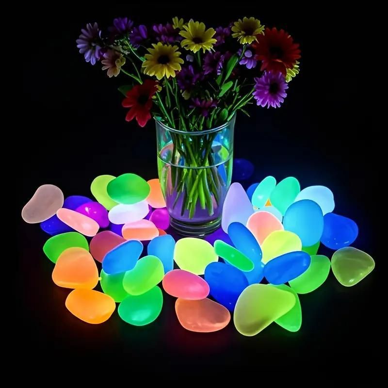 Mixed color glow stones for pathways glowing brightly around a vase of colorful flowers