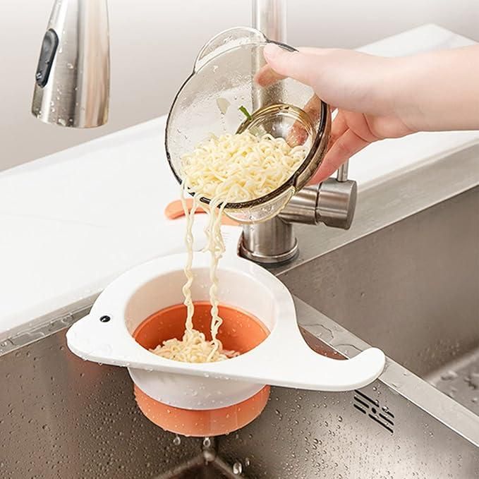 Whale drain basket for kitchen catching noodles in white and orange design under running faucet