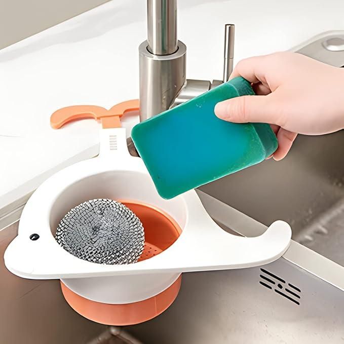 White whale drain basket for kitchen attached to sink holding a scrubber with hand using a green sponge