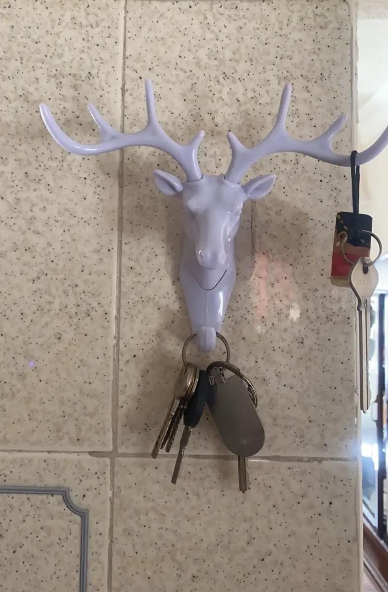 White deer head self adhesive coat hook mounted on tile wall holding keys