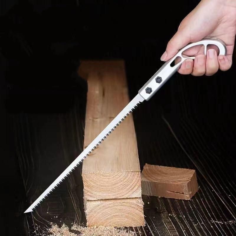 Hand holding a silver wood pruning saw cutting through a thick wooden plank on a dark surface