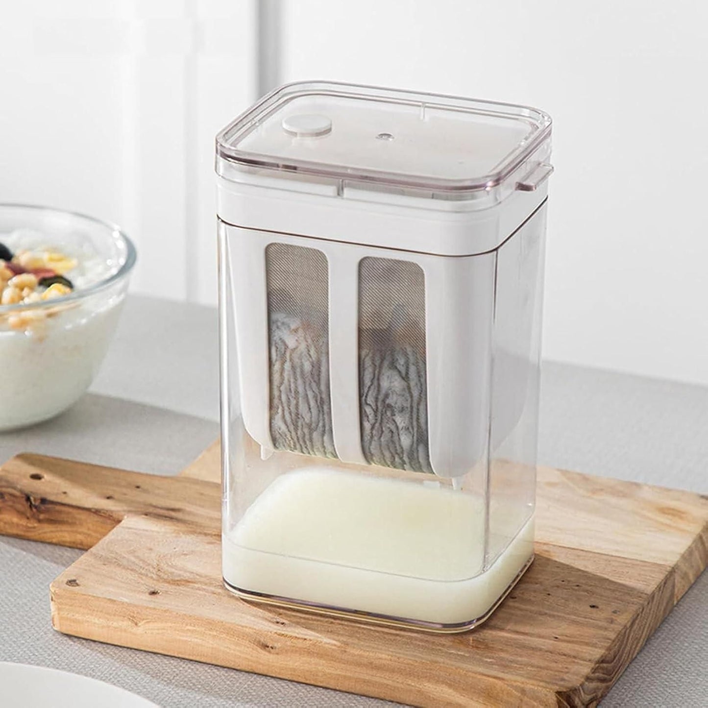 Compact yogurt maker with strainer for homemade Greek yogurt placed on wooden board