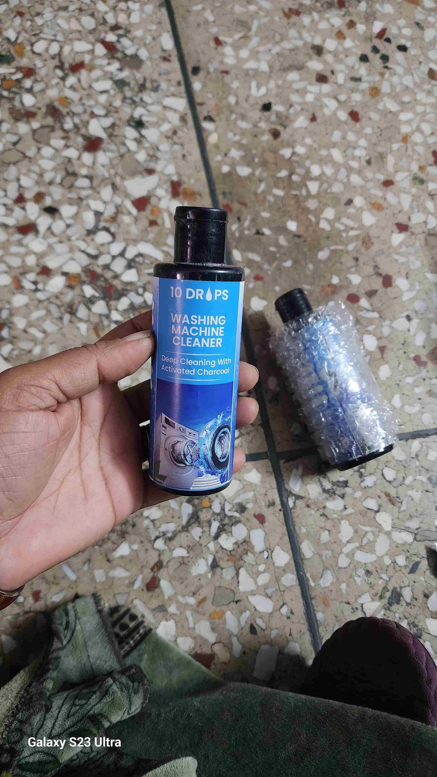 Washing machine cleaner liquid bottle held in hand with a shiny background