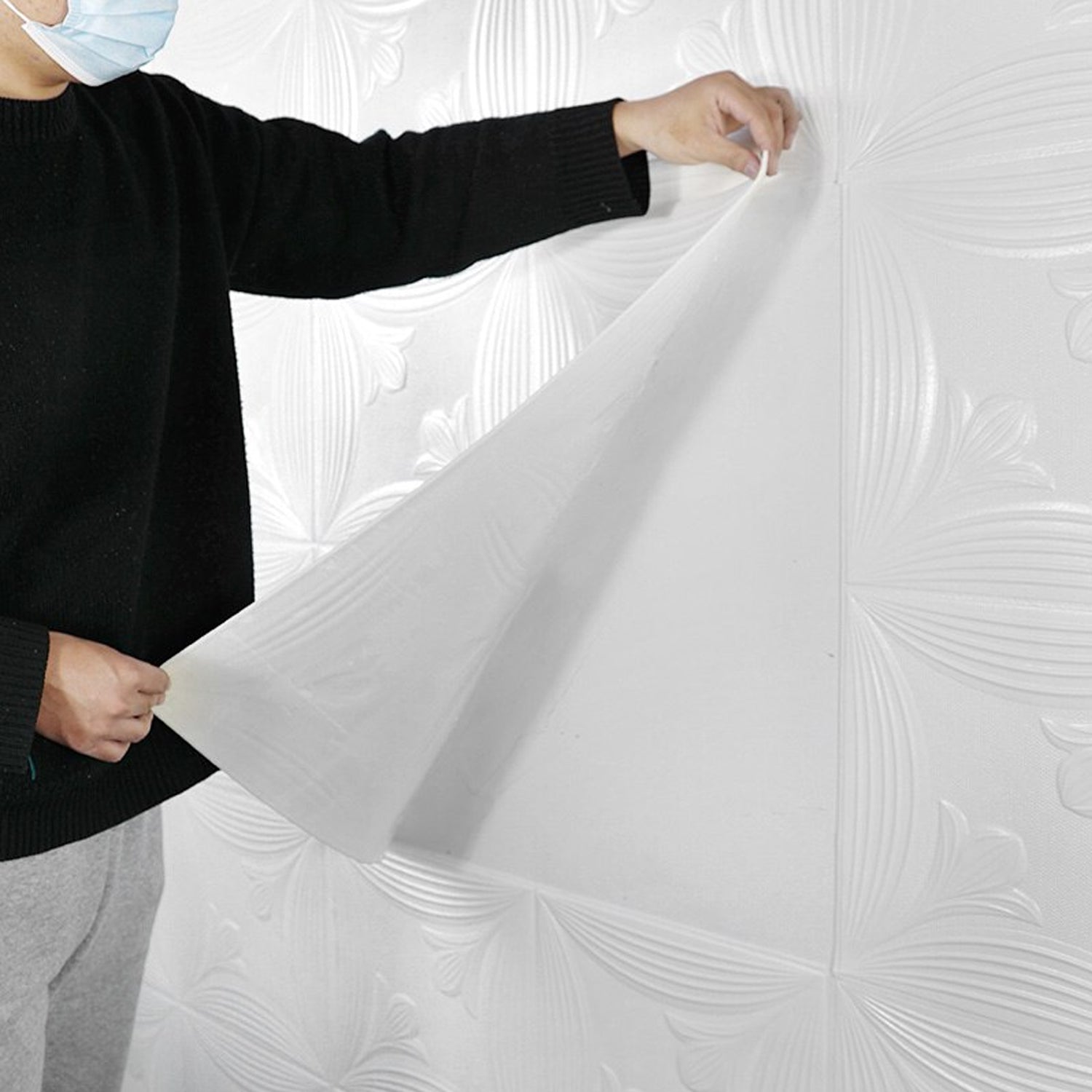 Person applying 3D foam wallpaper panels to a wall for a modern home improvement project