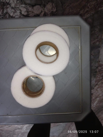 Three rolls of adhesive fabric fusion tape displayed on a textured surface for crafting projects