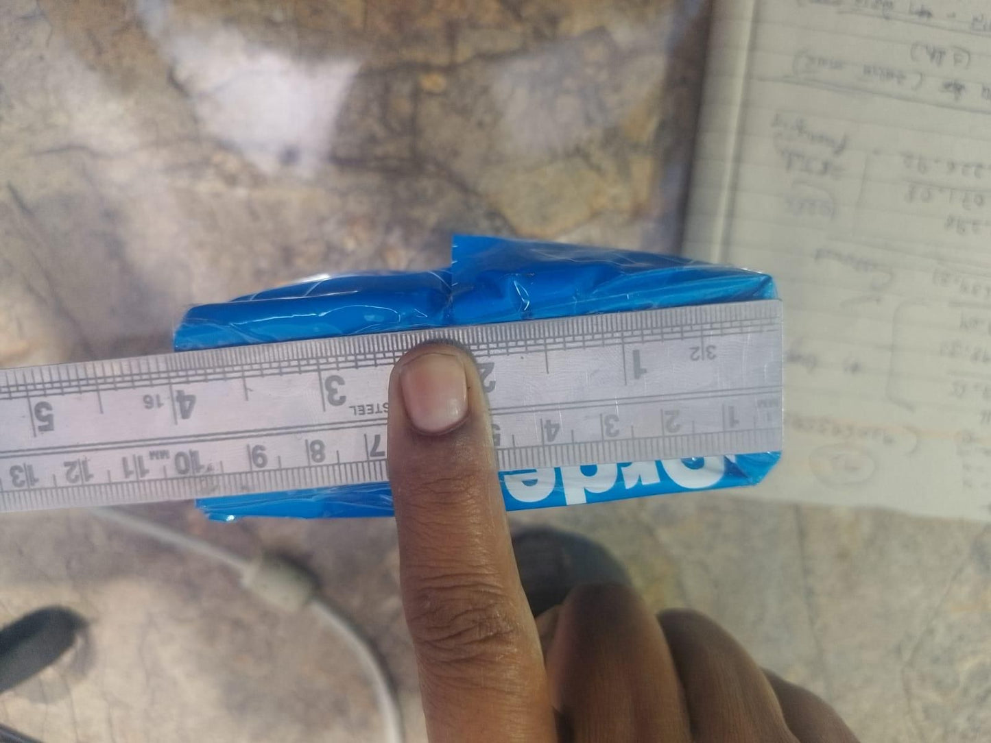 Close-up of a finger measuring adhesive fabric fusion tape with a ruler on a textured surface