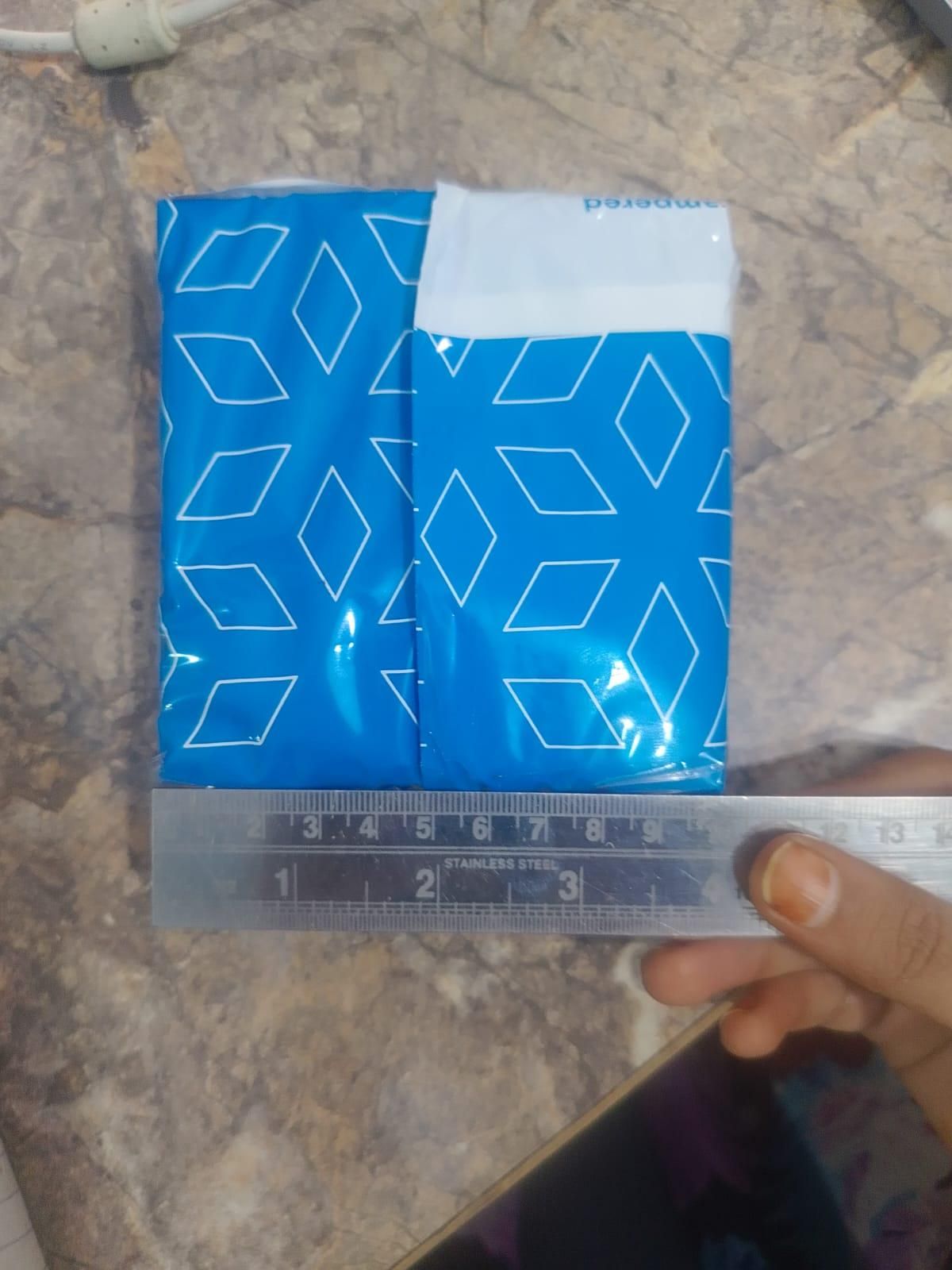 Adhesive fabric fusion tape packaged in blue plastic wrap, with a ruler for size reference
