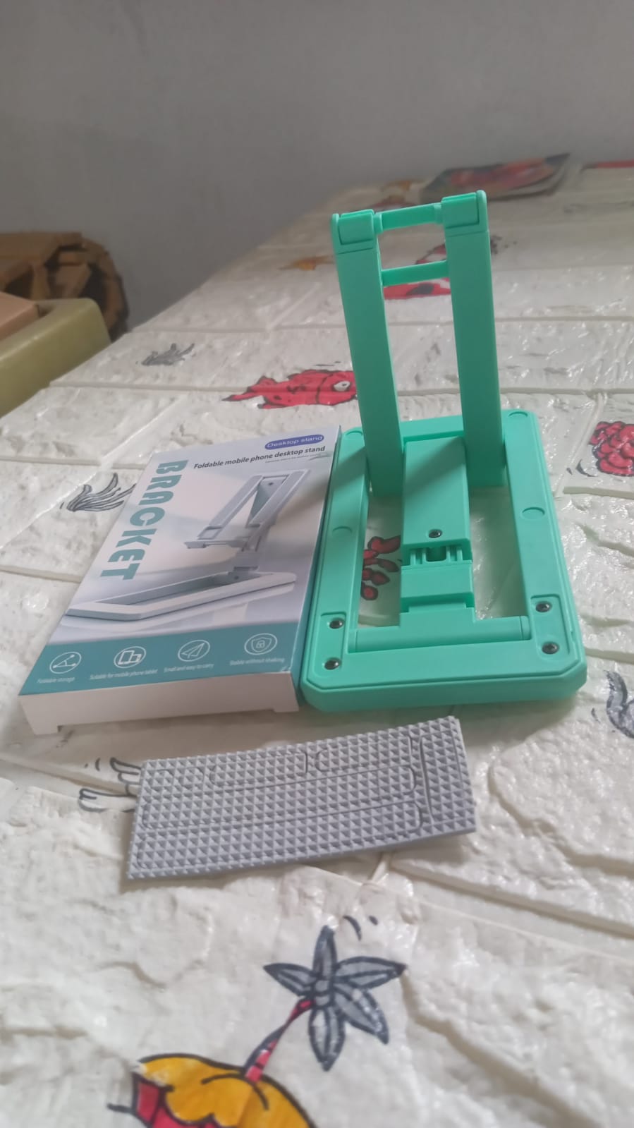 Adjustable foldable mobile stand in green with packaging and non-slip pad for stability