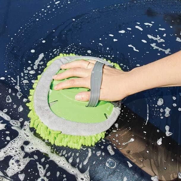Hand using an adjustable mop for outdoor use to clean a soapy dark surface