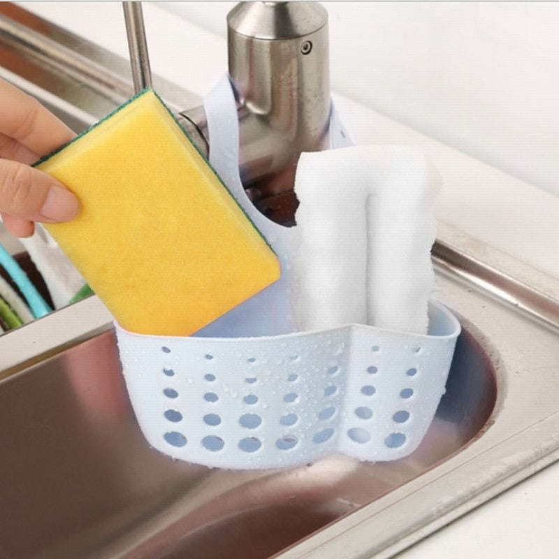 Blue adjustable sink caddy basket holding sponges and dish cloths by the sink for organized cleaning